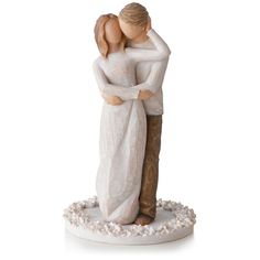 a figurine of a couple hugging each other on a white surface with pebbles