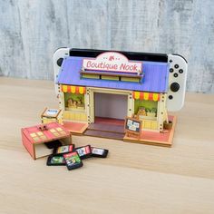 a small toy store sitting on top of a wooden table next to a nintendo wii game controller