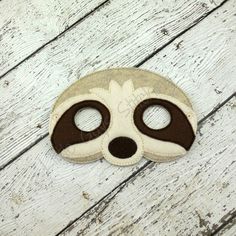 a slotty mask is sitting on a wooden floor with the eyes closed and brown trim around it