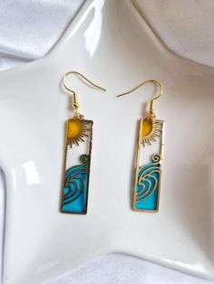 the earrings are made from gold and blue glass with an intricate design on it's sides