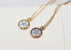 gold and rose gold necklaces with a blue forget me not flower inside resting on an off white microfiber necklace bag Forget Me Not Seeds, Jewelry Materials, Forget Me Not Flower, Stainless Steel Plate, Engraved Necklace, The Circle, A Circle, Forget Me Not, Circle Pendant