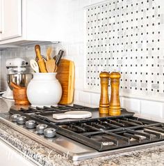 a stove top oven sitting inside of a kitchen next to a counter with utensils on it