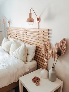 a bed with white sheets and pillows on top of it next to a night stand