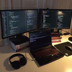 two computer monitors sitting on top of a desk next to a laptop and headphones