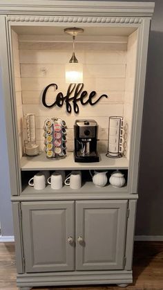 a small coffee bar in the corner of a room with white walls and gray cupboards