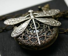 Perched on an ornate filigree pocket watch is an antiqued silver dragonfly. The watch really works :) Adjust time by popping up the button (pull it straight up), and open the watch by pressing the button down. Battery can be changed by a jeweler if needed. I inspect watches to ensure battery is operating before shipping out. The watch is 38mm in diameter and flies from a 24 inch large linked heavy-duty chain. I can make length modifications upon request. CUSTOMER FEEDBACK FOR THIS DESIGN: Love t Silver Antique Finish Pocket Watch Gift, Steampunk Silver Pocket Watch With Locket, Silver Steampunk Pocket Watch With Locket, Antique Silver Nickel-free Pocket Watch, Antique Nickel-free Silver Pocket Watch, Dragonfly Photos, Pocket Watch Necklace, Love T, Chain Extenders