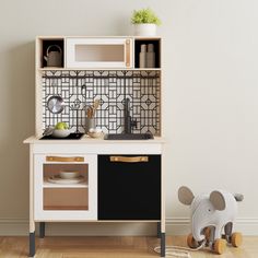 a wooden toy kitchen with an elephant figurine next to it and a white wall