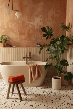 a bathroom with a bathtub, stool and potted plant