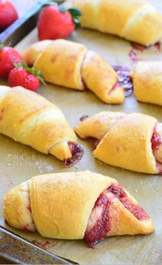 strawberry crescent pastries on a baking sheet with strawberries in the background