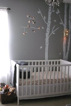 a baby's room with a white crib and tree decal on the wall