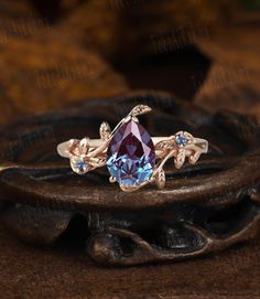 a ring with a blue stone and leaves on it sitting on top of a wooden table