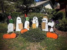 halloween decorations in the shape of ghostes and pumpkins on a lawn with a house in the background