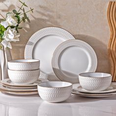 a white dinner set with flowers in the background