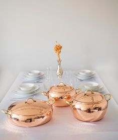 copper pots and pans are sitting on a table