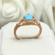 a blue opal ring sitting on top of a white cloth next to some flowers