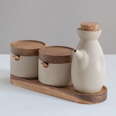 three ceramic containers with wooden lids on a tray