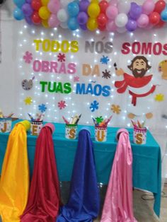 the table is set up with colorful decorations and balloons on it's sides, along with an arch that says todos nomos obras da tuas maos