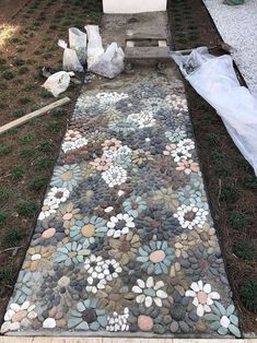 a walkway made out of rocks and stones with flowers on the ground next to it