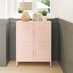 a pink locker next to a window with a lamp and books on top of it