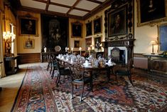 an ornate dining room with paintings on the walls and rugs in front of it