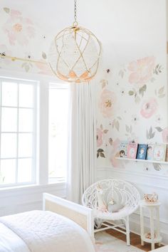 a white bed sitting next to a window in a room with flowers on the walls