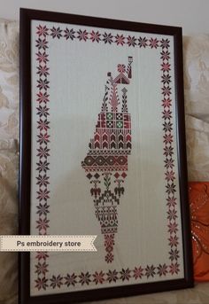 a cross - stitch picture with an image of a building in red and white on it