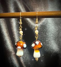 Golden Amber Mushroom Earrings Delight in the charm of these warm brown mushroom earrings, featuring soft amber brown lampwork glass beads with soft white spots on the mushroom caps. The gold-plated stainless steel metal ensures durability and elegance, making these earrings perfect for everyday wear.🍂 Incorporating upcycled pearls and gold spacer beads, this set is a step towards a more sustainable practice. These earrings not only add a whimsical touch to your style but also reflect a commitment to sustainability.🍄 Add these delightful earrings to your collection and enjoy the attention and admiration they bring.🧡 For more enchanting pieces and behind-the-scenes glimpses of my art practice, visit  my jewelry shop Instagram: @abigail.lynn.studio and my art Instagram: @merinilla__. Each Brown Mushroom, Golden Amber, Stuffed Mushroom Caps, Lampwork Glass Beads, Spacer Beads, Amber, Jewelry Shop, My Jewellery, Glass Beads