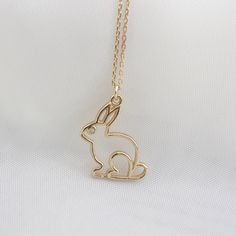 a gold rabbit necklace on a white background