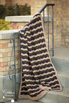 a crocheted blanket sitting on top of a stair case next to a brick wall