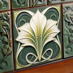 decorative tiles on the wall with flowers and leaves in gold, green and white colors