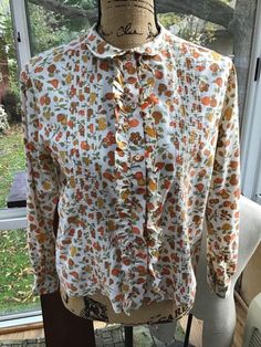 "Vintage 1960s ladies blouse. Cotton blend. Buttons down the front with ruffly fabric and Pin tucking along the sides. The design on the blouse are of Fruit and Pine Cones. The brand label is: *Laura Mae Life Blouse Washes Like A Hanky*. NO fading to the colors on the blouse. (Sunlight during photography may make it appear as such). Has been freshly laundered and ironed. CONDITION: No issues noted. SIZE TAG READS: 38 BUT PLEASE go by the measurements I provide below. I do not accept returns and Vintage Clothing Boutique, Blouse Cotton, Ladies Blouse, Brand Label, Orange Gold, Print Blouse, Brown Orange, Vintage 1960s, Blouse Top