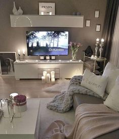 a living room filled with furniture and candles on top of the tv stand in front of a flat screen tv