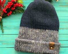 a knitted hat sitting on top of a wooden table next to red berries and greenery