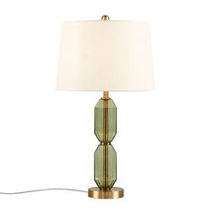 a green glass table lamp with a white shade on the bottom and a gold base