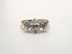 This impressive ring is set with simulated diamonds. I've listed them as cubic zirconia but they could be spinal. The centre stone is an oval that measures 8.5 X 5.8mm and the flanking stones are 4mm brilliant cuts. The total weight of the stone (if they were diamonds) would be 2ct. The shank is hallmarked 9ct gold with white gold settings. it weighs 2 grams and is a size Q now (US size 8) but I can size it up or down without further cost. It's refinished as new and so would be suitable as a gif Dazzling Cubic Zirconia Three-stone Ring, Formal Oval Cubic Zirconia Diamond Ring, Oval Topaz Ring With Diamond Accents For Anniversary, Oval White Topaz Jewelry For Wedding And Anniversary, Classic Topaz Ring With Diamond Accents And Cubic Zirconia, Oval Cubic Zirconia Diamond White Ring, Oval Three Stone Crystal Promise Ring, White Oval Crystal Ring With Diamond Cut, Dazzling Oval Cubic Zirconia Crystal Ring