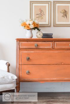 an old dresser with flowers and pictures on the wall