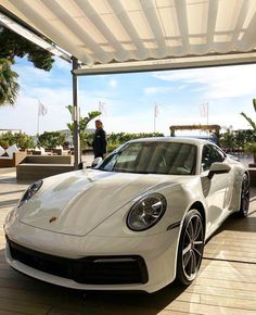 a white porsche parked in front of a man standing next to it's car