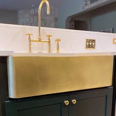 a kitchen sink with gold faucet and black cabinets