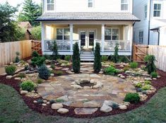 a stone patio and landscaping area in front of a house