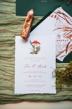 the wedding stationery is laid out on top of an envelope and some other items