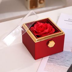 a red box with a rose inside sitting on a table