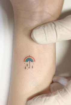 a person with a small tattoo on their arm holding an umbrella and raindrops