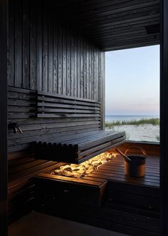 a wooden sauna with an open door leading out to the ocean and sand dunes