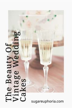 two champagne glasses sitting next to each other on top of a wooden table with a cake in the background