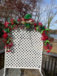 a white chair sitting on top of a wooden table next to a fence covered in red and green decorations