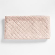 the pink quilted blanket is laying on top of a white wall