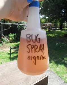 a bottle with the words bug spray on it in front of a yard and trees