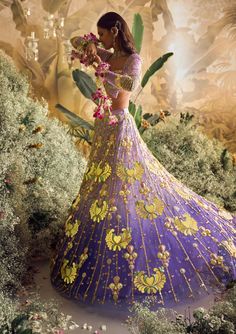 Step into a world of enchantment with our shaded lilac tulle lehenga set - a spellbinding fusion of colors and textures. Watch as custom cut acrylic pieces, gold metal embellishments, and rich fabric appliques come together to create a truly mesmerizing design. Paired with our signature butterfly full-sleeved blouse in lilac silks, and a delicately embroidered tulle dupatta that glistens with metals, pearls, and sequins. Get ready to dazzle and make a statement on your special day! Lavender Lehenga With Zari Work For Wedding, Lavender Wedding Set With Sheer Dupatta, Lavender Wedding Sharara With Sheer Dupatta, Lavender Sharara With Sheer Dupatta For Wedding, Wedding Lavender Sharara With Sheer Dupatta, Lavender Embroidered Sharara For Wedding, Lavender Sharara With Intricate Embroidery For Wedding, Lavender Wedding Choli With Resham Embroidery, Elegant Lavender Designer Lehenga