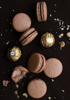 chocolates and macaroons are arranged on a black surface with scattered confetti