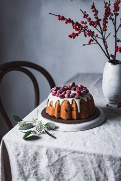 a bundt cake with frosting and cranberries sits on a white plate